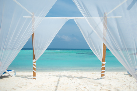 White tent for wedding ceremonies or romantic evening on a maldivian island. Beautiful view with white sand and blue sea.の写真素材