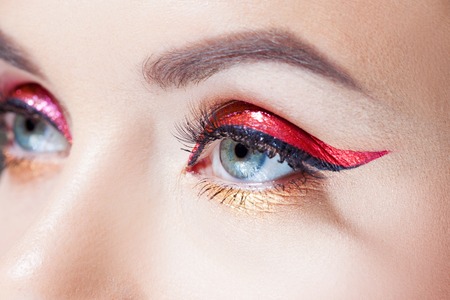 Amazing Bright eye makeup in luxurious red arrow. Red and gold shining tones, eye shadow. Close upの写真素材