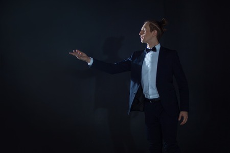 lonely Young man in a suit pulls his hand somewhere and waits for someone. Dark mystical background