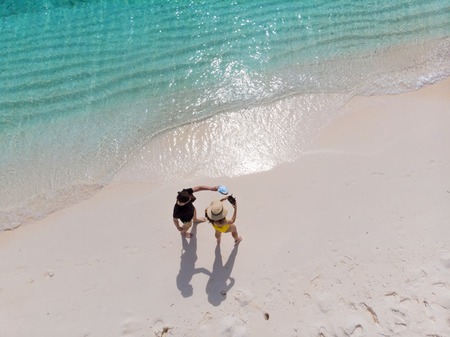 Beautiful beach with white sand and clear blue sea. Couple on the beach, top viewの写真素材