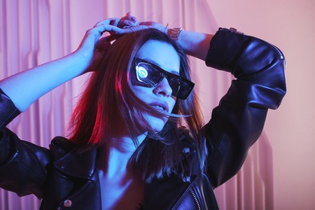 Beautiful girl dancing in retro wave on the neon light. Fashion portrait of trendy young woman in...