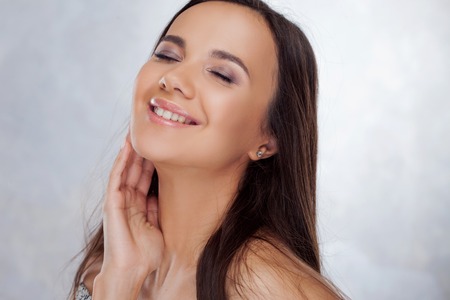Young charming brunette smiling. Beauty portrait of a young beautiful woman with gorgeous long and smooth hair.の写真素材
