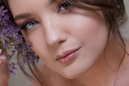 Cute young woman portrait close-up, fresh spring image with flowers. Beautiful girl with clean well-groomed skinの写真素材