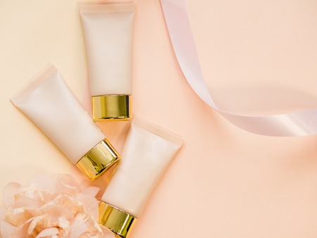 Three shades of concealer in the tube, tonal Foundation for perfect makeup, still life on a soft cream background. The concept of makeupの写真素材