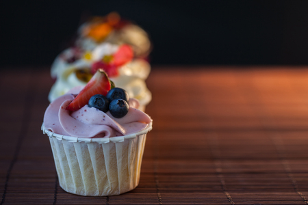 Beautiful and delicious cupcakes on the table. A set of delicious sweet desserts with cream.の写真素材