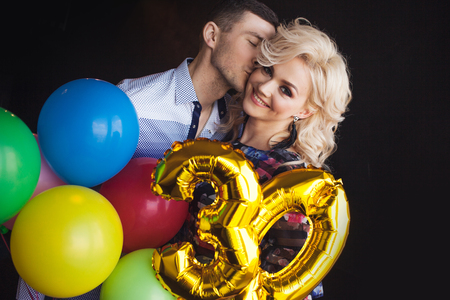 A young man kisses and congratulates her beloved on his birthday. Man and woman at a birthday partyの写真素材