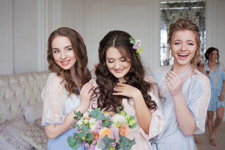 Girlfriends hug bride, bachelor party. Happy beautiful girls in the apartmentの写真素材