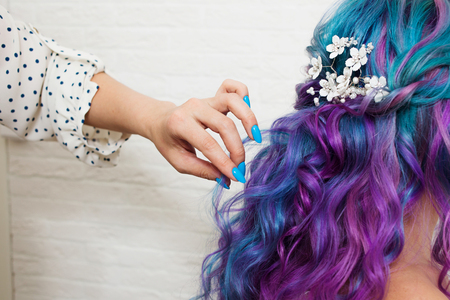hair stylist doing styling on long curls. Bright multi-colored hair coloring in the salonの写真素材