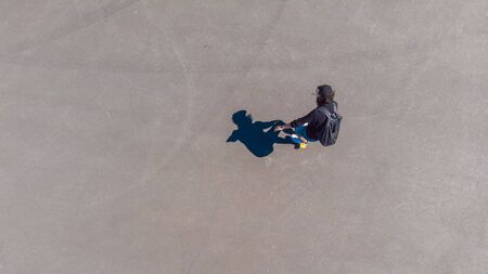 Guy rides a skateboard, top view, shadow on the pavement. Youth lifestyle, copy space on the leftの写真素材