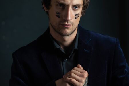 A young handsome man with a slight unshaven face and decisiveness in his eyes, with a black war...