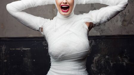 screaming woman in bandages. Glamorous mummy. Portrait of a young beautiful woman in bandages all...