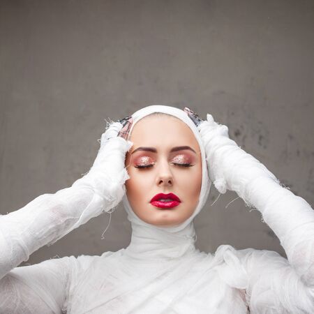 Glamorous mummy. Portrait of a young beautiful woman in bandages all over her body. Halloween or...