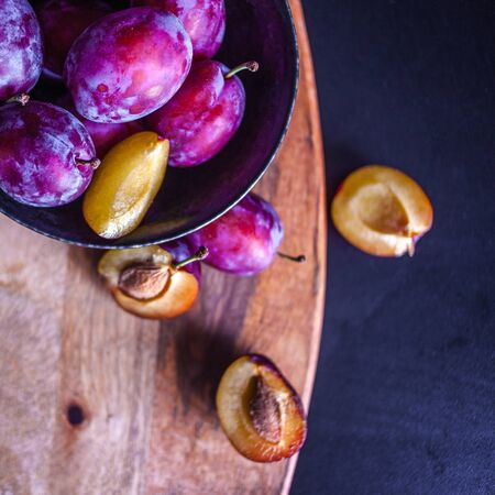 Delicious juicy blue plums in a bowl on the table, textured wooden table, natural materials and natural eco-friendly products, healthy food, fruitの写真素材