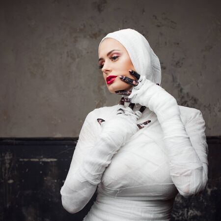 Glamorous mummy. Portrait of a young beautiful woman in bandages all over her body. Halloween or plastic surgery conceptの写真素材