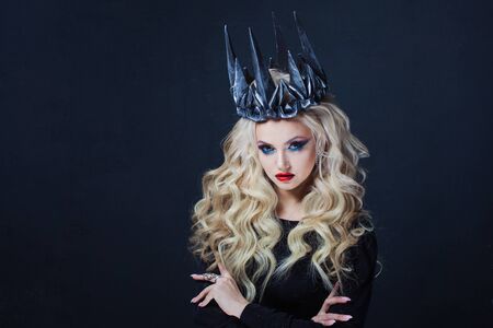 Portrait of a Gothic Queen. Beautiful young blonde woman in metal crown and black cloak. Mystical imageの写真素材