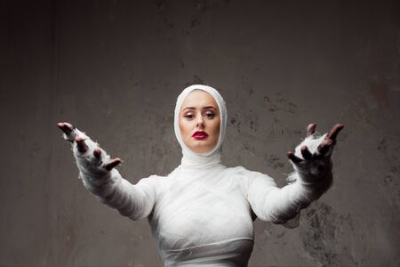 Beautiful young woman in bandages. Girl in a mummy costume, Pulling hand. Halloween or plastic...