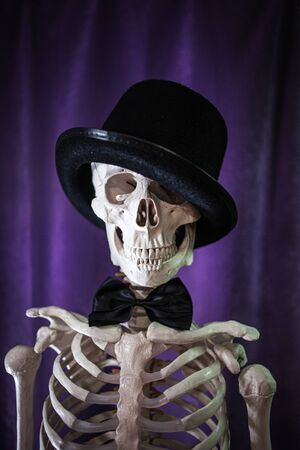 Funny human skeleton in a bowler hat and bow tie. Skeleton invites to Halloween.の写真素材