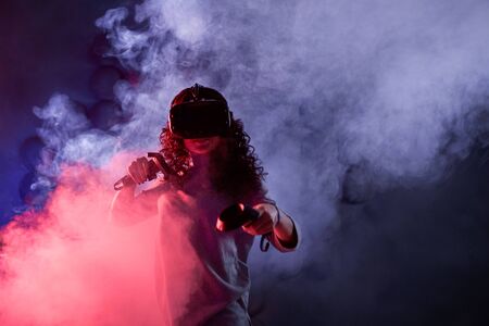 Virtual reality game. A girl in a VR helmet plays a game or explores the environment. Portrait in...