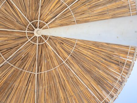 Straw umbrella for sun protection, texture view from sun lounger