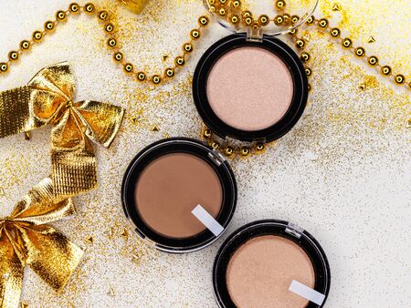 Make up for new year holiday party, makeup set. Festive new-year flat lay. Gold decor on white background. Powder, concealer and highlighterの写真素材