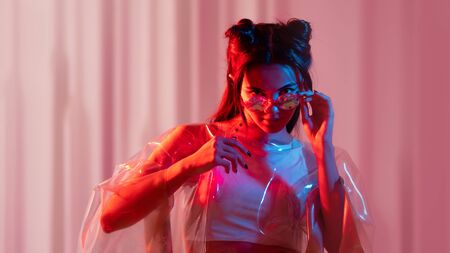 Cyberpunk and neon, a young trend girl in a transparent latex Cape. Futuristic neon style, bright red backlight.の写真素材