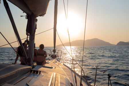 Girls sit on the deck of the yacht and enjoy the sunset. Boat trip on a yacht under sail, a fragment...
