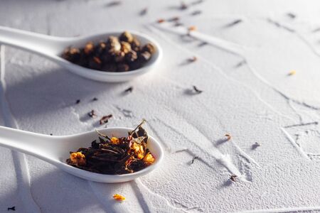 Still life with different varieties of tea, dry tea leaf. making of tasty and healthy hot drink. Welding in white spoons on a white textured concrete backgroundの写真素材