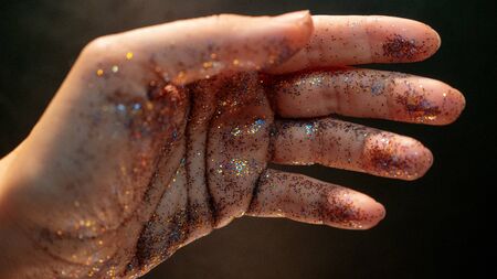Female hand covered with sequins. The movement of the palm of your hand and Shine multicolored glitter, mystical and abstract mood. Defocused lightの写真素材
