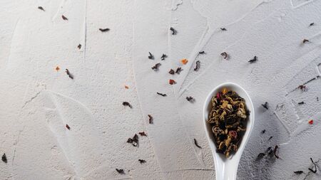 Green tea with fruit additives, dry tea leaf. making of tasty and healthy hot drink. Welding in white spoons on a white textured concrete backgroundの写真素材