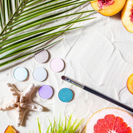 Charming beach. Round single shadows of different shades with bright fruits, a starfish, and palm leaves lie on the white sand. Close-up, top view, desktop wallpaper. Copyspace.の写真素材