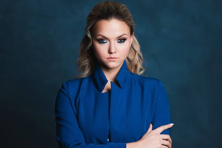 Business portrait of a stylish young blonde in a blue jacket on a blue background