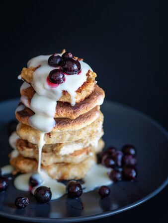 Oatmeal pancakes with berries and sweet sauce, homemade Breakfast pastries, dark backgroundの写真素材