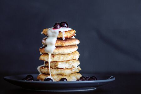 Oatmeal pancakes with berries and sweet sauce, homemade Breakfast pastries, dark background