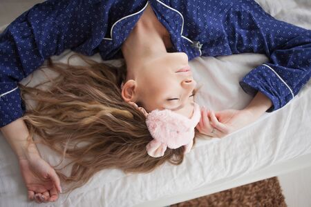 Portrait of a beautiful woman in pajamas at home, lying in bedの写真素材