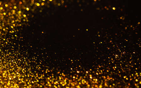 Sparkling gold glitter on a black background, magic abstract background. Round frame made of gold particles, copy space in the center, template for greeting or letteringの写真素材