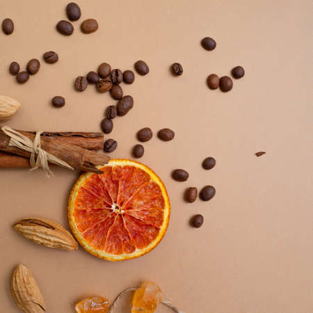 Citrus and spicy background with coffee beans and spices, warm ochre background. Copy space. Cinnamon, nuts and sugar crystalsの写真素材