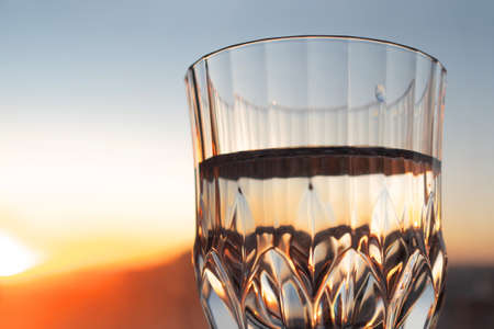 glass of clear clear water against the background of the evening sky. Drink clean water every dayの写真素材