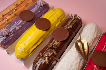 set of eclairs with different fillings on a pink background. Sweet French pastries with custard