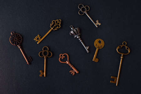 Many different old keys from different locks, scattered chaotically, flat lay. Finding the right key, encryption, concept. Retro vintage copper keys in black backgroundの写真素材
