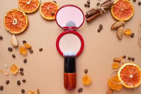 Cosmetics for natural makeup, powder . fluffy makeup brush on top. Warm background with nuts coffee...