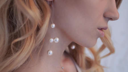 Beautiful elegant bride in a simple white wedding dress with sleeves portrait with modern pearl earringsの写真素材