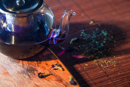 Blue Thai tea in a glass teapot. Freshly brewed tea, delicious and healthy hot drink. Hot drink on Mat, dark still lifeの写真素材