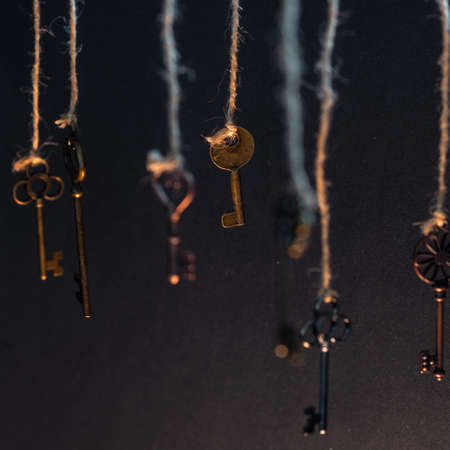 A lot of different old keys from different locks, hanging from the top on strings. Finding the right...