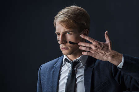 businessman draws two stripes on his cheeks, war paint. Competition in business, concept. A young...