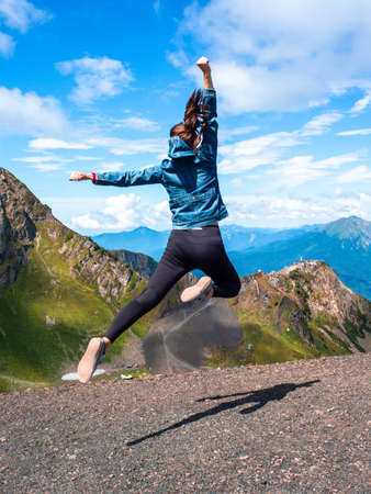 Superhero jump in the mountains against the sky. Ambition and purpose, concept. A young female...