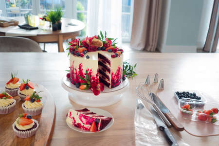 Big beautiful red velvet cake, with flowers and berries on top. Slice on a plate, dessert. Cake and muffins, cooking at homeの写真素材