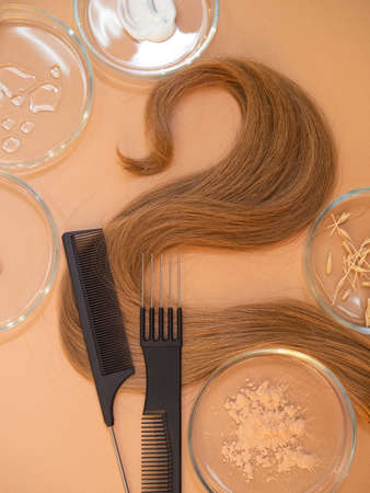 Eco-friendly and modern cosmetics for hair care, a set of ingredients and bottles on a brown background. Hair and combsの写真素材