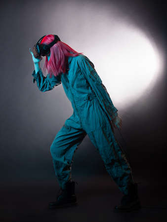 Virtual reality and futurism. Cyberpunk concept, a gamer with pink hair. Young woman in overalls and virtual reality glasses, is in a simulation, black backgroundの写真素材