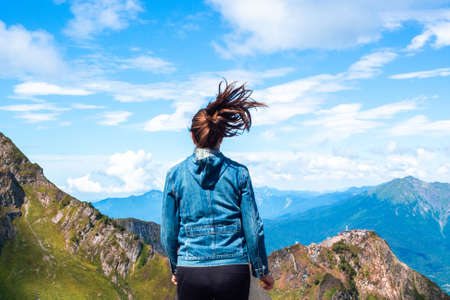 A young female tourist on top of a mountain on the panorama background. Happiness and a sense of freedom, travel in the mountains, the power of natureの写真素材