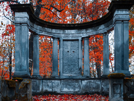 The old Catholic cemetery in the fall. Abandoned graves under a layer of fallen leaves. Stone monument with columns on the family burial groundの写真素材